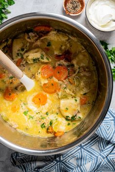 a pot filled with chicken and vegetables on top of a blue towel next to some sour cream