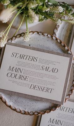 the wedding stationery is laid out on top of each other, with flowers and greenery