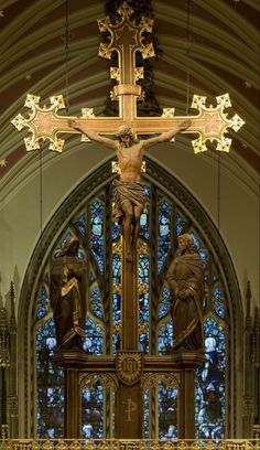 the cross is in front of an ornate stained glass window