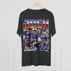 The Josh Allen retro-type graphic t-shirt is a must-have for any dedicated Buffalo Bills fan or admirer of the NFL's rising star quarterback, Josh Allen. This vintage-inspired t-shirt combines modern aesthetics with a nostalgic twist to celebrate the dynamic player's achievements and style. Here's a detailed description of this stylish piece: Front Design: The focal point of this retro-type graphic t-shirt is a striking, stylized illustration of Josh Allen in a classic football pose. The image captures his determined expression and iconic throwing motion, showcasing his athleticism and prowess on the field. Color Palette: The t-shirt boasts a carefully selected color palette that includes rich royal blue, deep red, and crisp white. These colors not only pay homage to the Buffalo Bills' tea Graphic Print T-shirt For Football Season Fan Events, Throwback Graphic Print Tops For Football Season, Retro Team Name T-shirt For Streetwear, Sports Fan Graphic T-shirt, Throwback Short Sleeve Fan Merchandise T-shirt, Throwback Fan Merchandise T-shirt With Short Sleeves, Throwback Short Sleeve Team Name T-shirt, Throwback Short Sleeve T-shirt With Team Name, Football Season T-shirt With Graphic Print For Fan Events