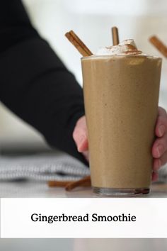 a person holding a drink with cinnamon sticks on the rim and text gingerbread smoothie