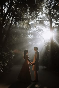 a man and woman standing in front of trees holding hands