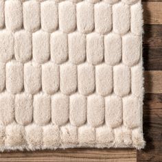 a white rug on top of a wooden floor next to a wood planked wall