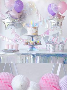 a table topped with cake and balloons on top of a white table covered in confetti