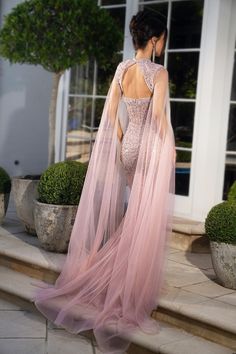 a woman in a pink dress standing on steps with her back turned to the camera