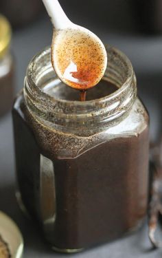 a spoon full of brown liquid sitting on top of a jar