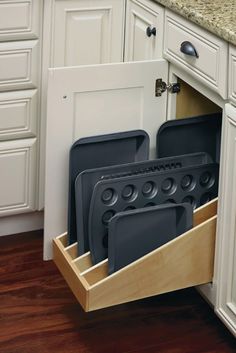 an open drawer in the middle of a kitchen with black plates and pans on it