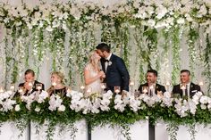 a bride and groom kissing in front of their wedding party at the head table with candles