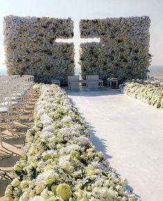 an outdoor ceremony with white and green flowers on the ground, surrounded by rows of chairs