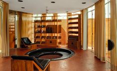 a living room filled with lots of furniture next to large open bookshelves and windows