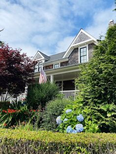 a house that is surrounded by bushes and flowers