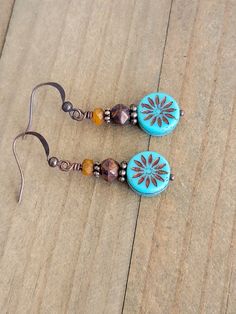 These rustic Czech glass bead dangle earrings feature copper accents and a combination of burnt orange and rustic brown colors. The addition of turquoise aster coin beads, washed in bronze, adds a unique touch to these earrings. Perfect for adding a touch of Bohemian charm to any outfit. Czech glass beads Copper accents Copper ear hooks Length 1.75" Created in studio - Wilmington, NC Czech Beads Jewelry, Earthy Earrings, 2024 Jewelry, Bead Dangle Earrings, Rustic Earrings, Diy Jewelry Ideas, Copper Accents, Wilmington Nc, Glass Buttons