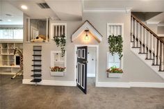 a dog house in the middle of a living room with stairs and potted plants