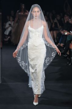 a woman walking down a runway wearing a veil