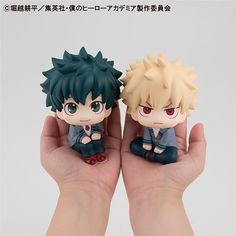 two anime figurines sitting on top of each other in their hands, one is holding