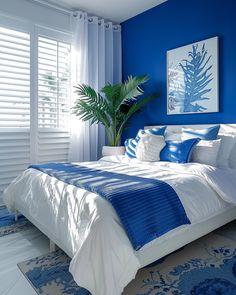 a bedroom with blue walls and white bedding is decorated in shades of blue, while palm leaves are on the window sill