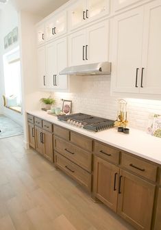 a kitchen with white cabinets and wood floors