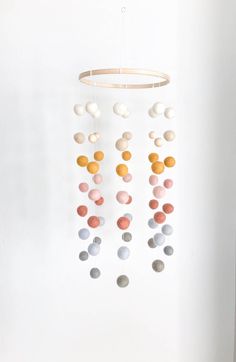 a mobile made out of balls hanging from the ceiling in a room with white walls