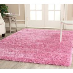 a living room with a pink rug on the floor and a white chair next to it