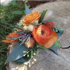 an orange flower bouquet sitting on top of a tree stump