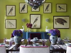 the dining room table is set with purple and white flowers in vases on top