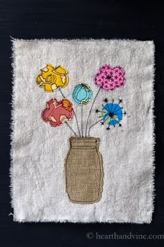 a vase filled with flowers sitting on top of a white piece of cloth next to a black wall