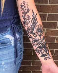 a woman's arm with flowers on it and a hand holding an object in front of her