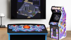 two arcade machines sitting on top of a wooden table