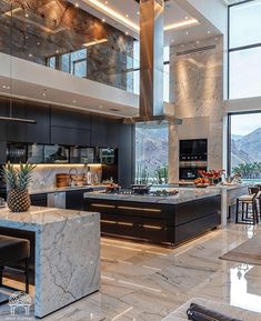 a large kitchen with marble counter tops and black cabinets, along with an island in the middle