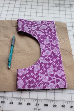 a piece of brown paper with purple flowers on it next to a pen and ruler