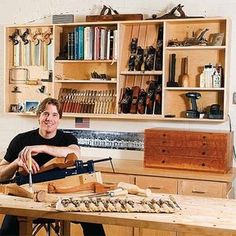 a man is sitting at a table with some woodworking tools