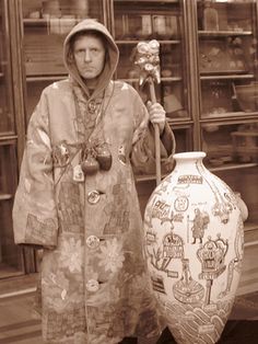 an old photo of a woman holding a stick next to a vase