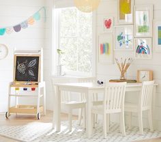 a child's room with white furniture and pictures on the wall, including a chalkboard