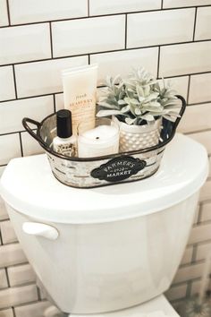 a white toilet sitting in a bathroom next to a tiled wall with a potted plant