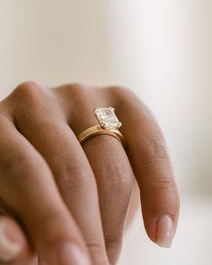 a close up of a person's hand holding a ring with a diamond on it