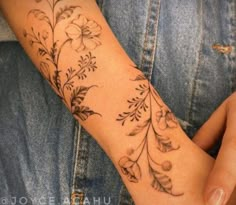 a woman's arm with flowers and leaves on it