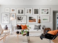 a living room filled with furniture and lots of framed pictures on the wall above it