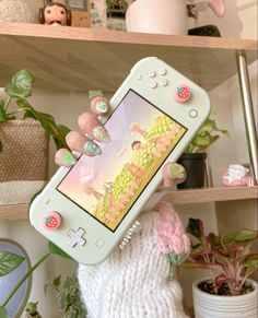 a person holding up a cell phone in front of a shelf with plants and potted plants