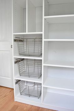 an organized closet with white shelves and wire baskets on the bottom shelf, along with wood flooring