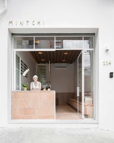 a woman is sitting at the counter in front of a storefront with an open door