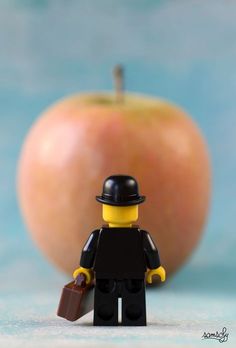 a lego man standing next to an apple