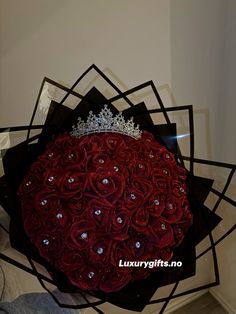 a large bouquet of red roses with a tiara on top