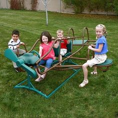 four children are sitting on a small wooden swing set in the grass with their arms around each other