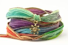 multicolored bracelets with gold flower charm on each side and ribbon around the clasp