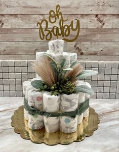 a three tiered cake made out of rolls of toilet paper with the word oh baby on top