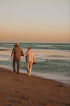 two people walking on the beach holding hands