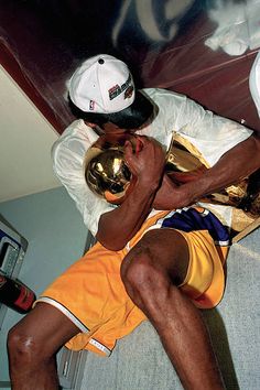 a man laying on the floor with a basketball in his hand and wearing a white hat