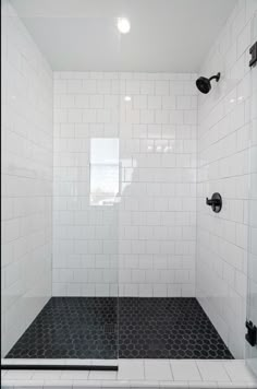 a white tiled shower with black accents