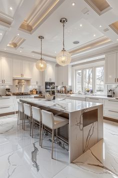 a large kitchen with white cabinets and marble counter tops, along with two chandeliers hanging from the ceiling