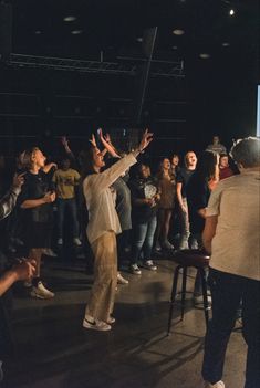 a group of people standing around each other with their arms in the air and hands up